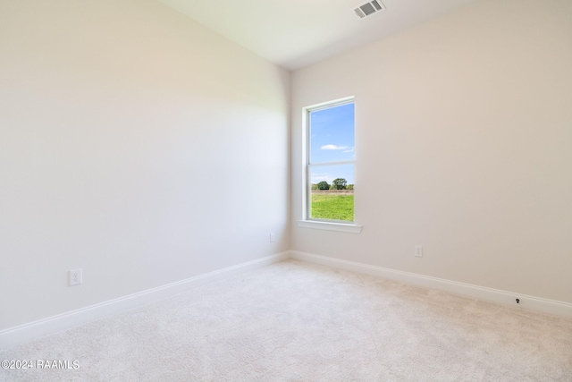 empty room featuring baseboards, visible vents, and light carpet