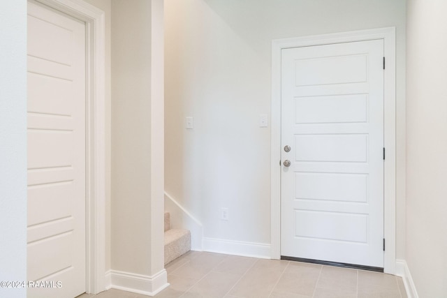 doorway to outside with stairway, light tile patterned flooring, and baseboards