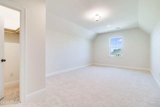 additional living space featuring visible vents, baseboards, light colored carpet, and vaulted ceiling