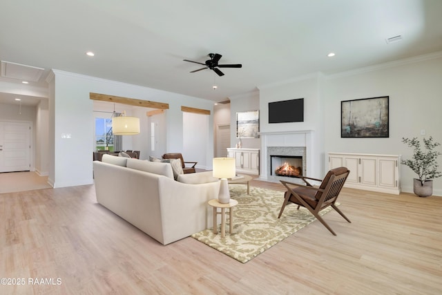 living room with attic access, light wood-style flooring, crown molding, and a premium fireplace