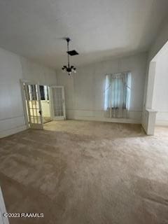 empty room with a chandelier and light carpet