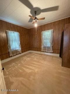 spare room featuring ceiling fan and wood walls