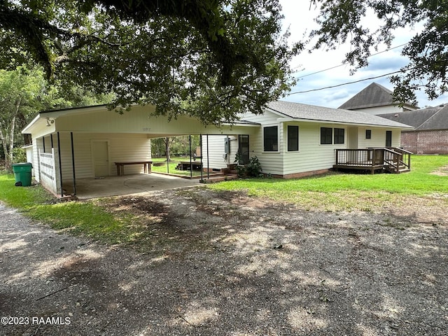 ranch-style home featuring a carport, a front yard, and a wooden deck