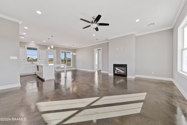 unfurnished living room featuring ceiling fan with notable chandelier and crown molding