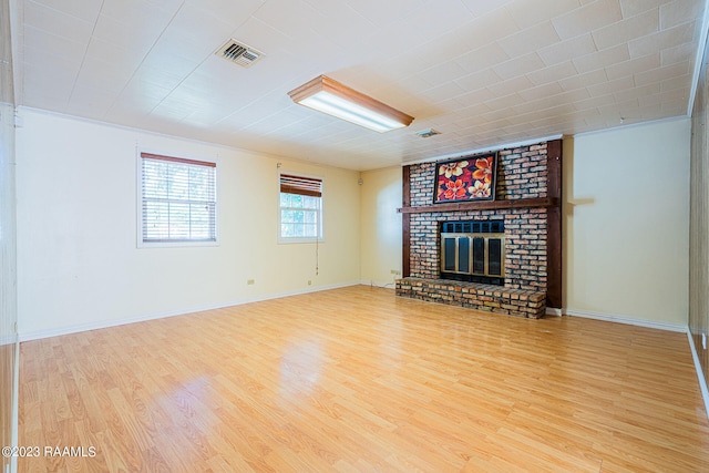 unfurnished living room featuring light hardwood / wood-style flooring, brick wall, and a fireplace