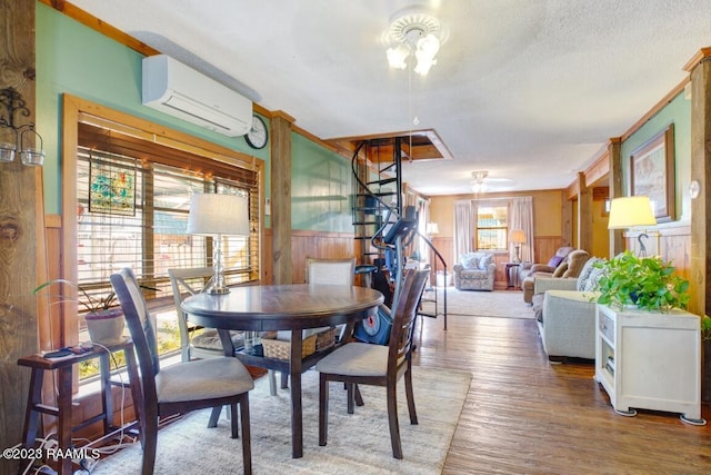 dining room with a wall mounted air conditioner, wood-type flooring, and a textured ceiling