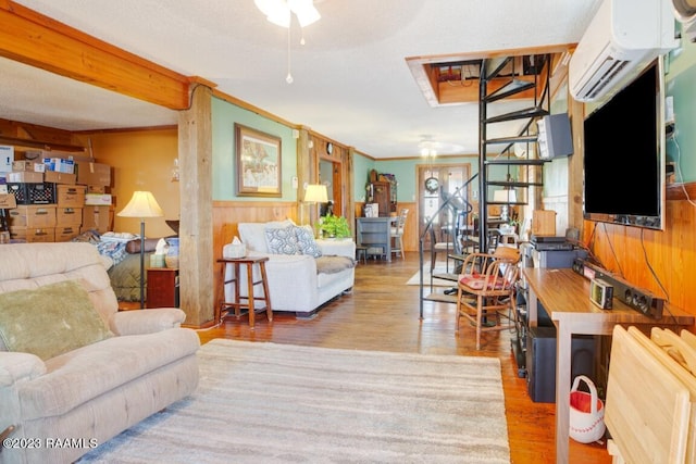 living room with crown molding, an AC wall unit, wooden walls, and light wood-type flooring