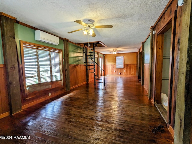 empty room featuring ceiling fan, dark hardwood / wood-style floors, wooden walls, and a wall unit AC