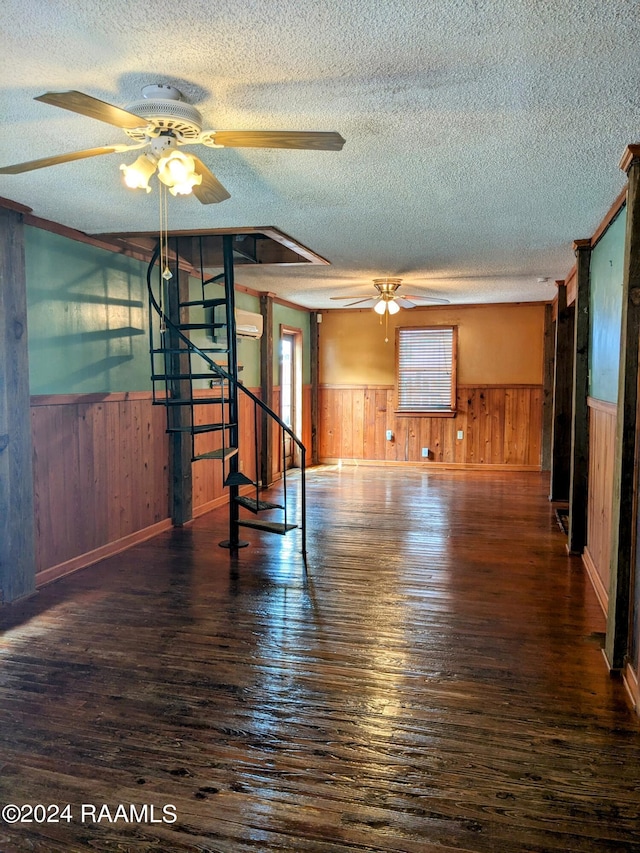 unfurnished room featuring ceiling fan, dark hardwood / wood-style floors, a textured ceiling, and wood walls