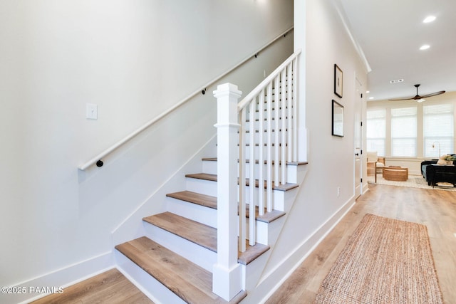 stairway with ceiling fan, crown molding, and hardwood / wood-style flooring