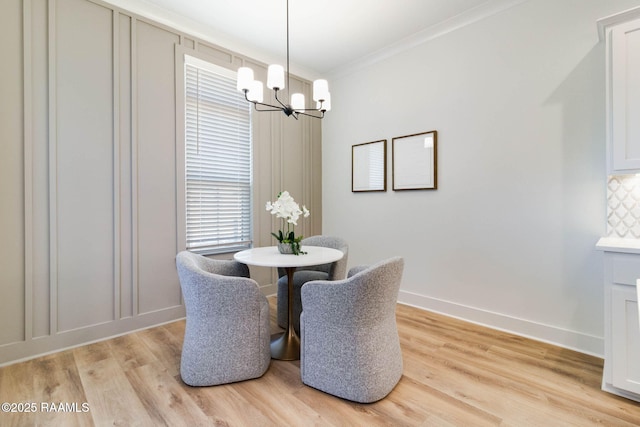 dining space with light hardwood / wood-style floors, ornamental molding, and a chandelier