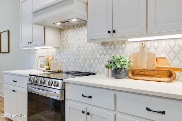 kitchen featuring electric range, white cabinetry, custom range hood, and tasteful backsplash