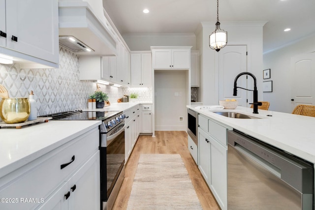 kitchen with pendant lighting, custom exhaust hood, sink, appliances with stainless steel finishes, and white cabinetry