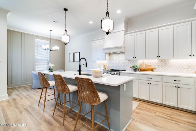 kitchen featuring white cabinets, an island with sink, and pendant lighting