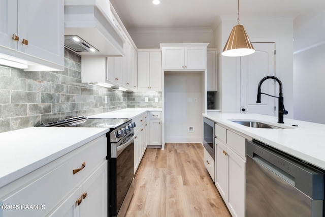 kitchen featuring sink, stainless steel appliances, premium range hood, pendant lighting, and white cabinets