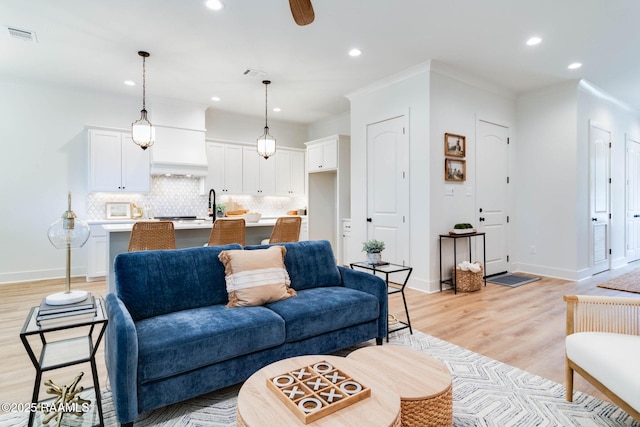 living room featuring ceiling fan, light hardwood / wood-style floors, and crown molding