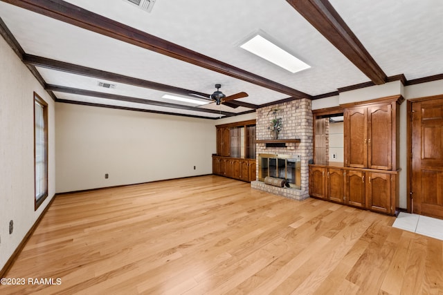 unfurnished living room featuring beam ceiling, ceiling fan, a brick fireplace, and light hardwood / wood-style floors