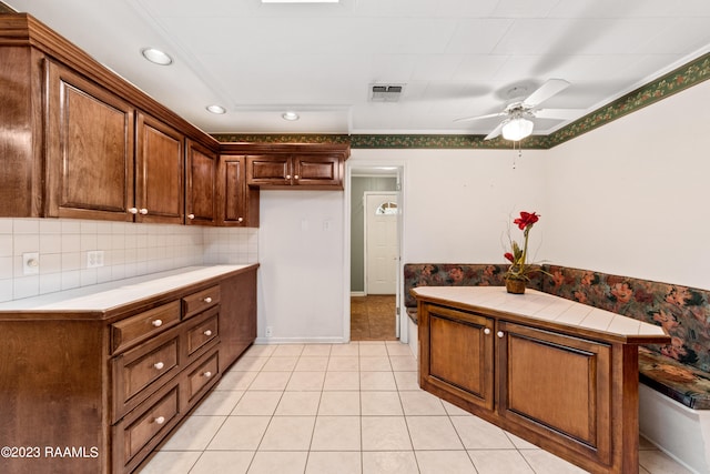 kitchen featuring tasteful backsplash, light tile patterned floors, tile counters, and ceiling fan