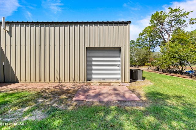 garage with central air condition unit and a lawn