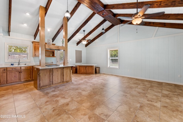 kitchen with decorative light fixtures, black electric cooktop, a kitchen island, ceiling fan, and beam ceiling