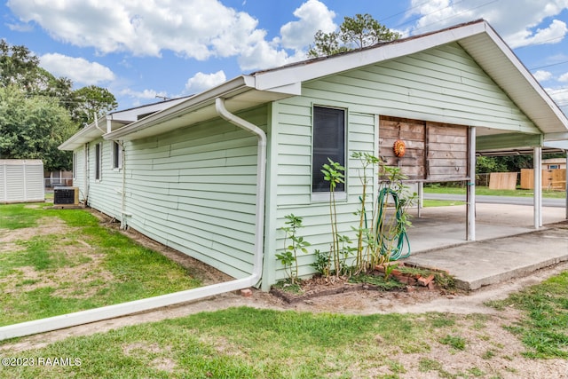 view of property exterior featuring a lawn, central air condition unit, and an outdoor structure