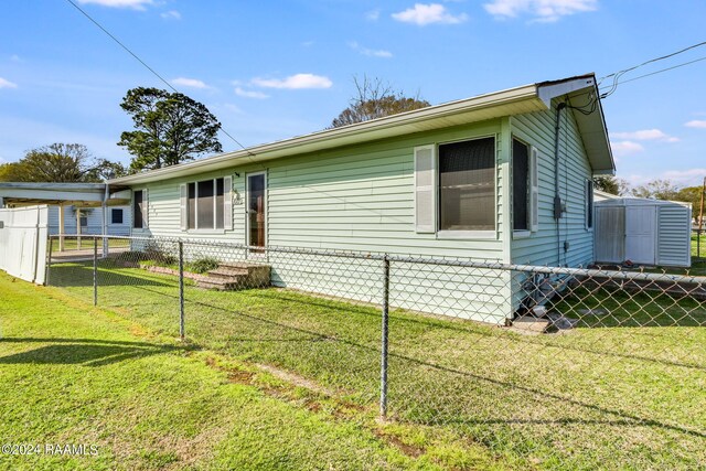 view of side of home with a storage shed and a yard