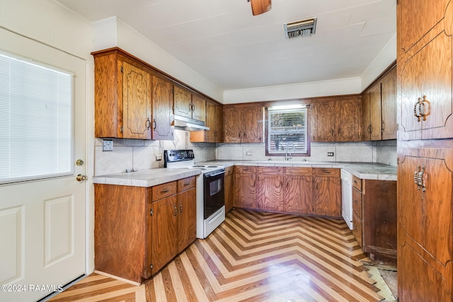 kitchen featuring light parquet flooring, backsplash, electric range, and sink