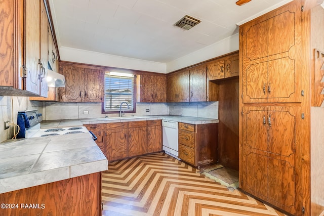 kitchen featuring wall chimney range hood, light parquet floors, white appliances, backsplash, and sink