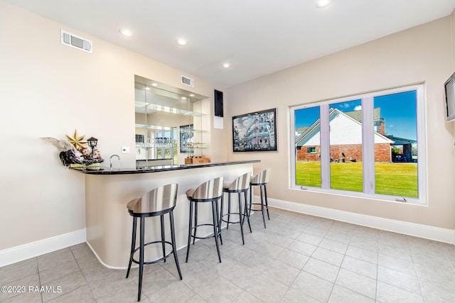 kitchen featuring light tile floors, a breakfast bar, kitchen peninsula, and a wealth of natural light