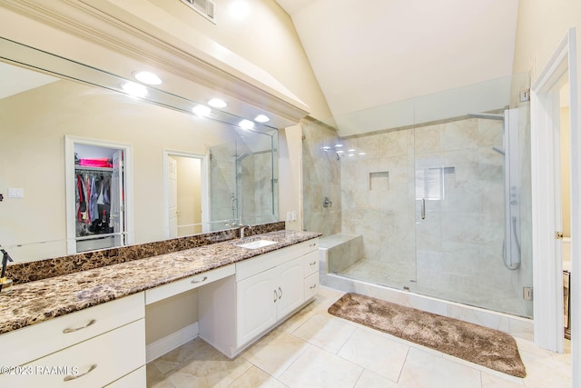 bathroom with tile flooring, vaulted ceiling, a shower with shower door, and vanity