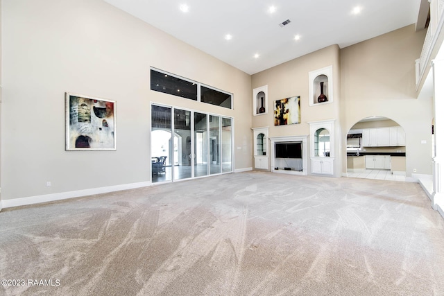 unfurnished living room with light colored carpet and a towering ceiling