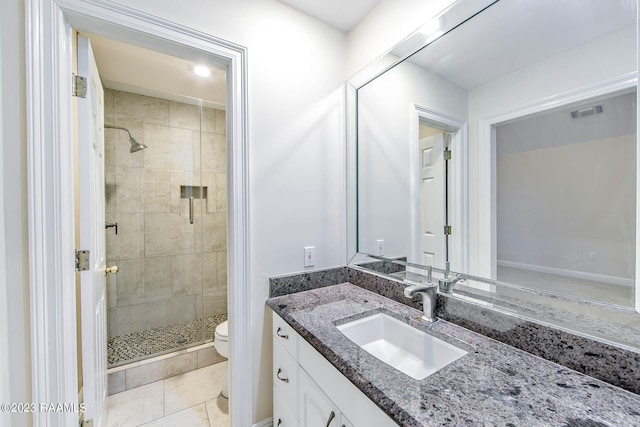 bathroom with tiled shower, tile flooring, toilet, and large vanity