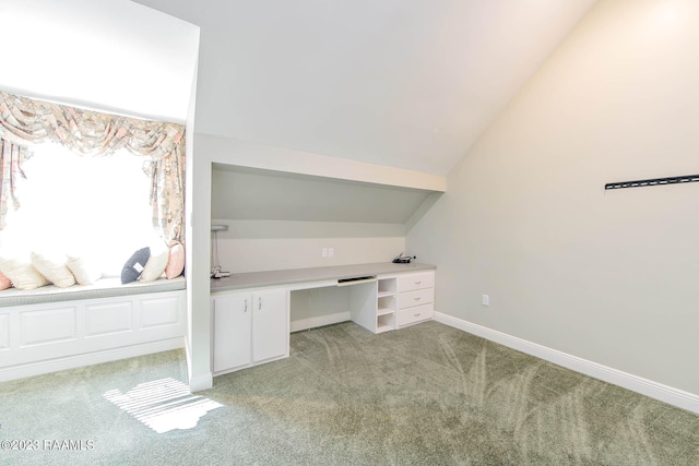 unfurnished office featuring lofted ceiling, light carpet, and built in desk