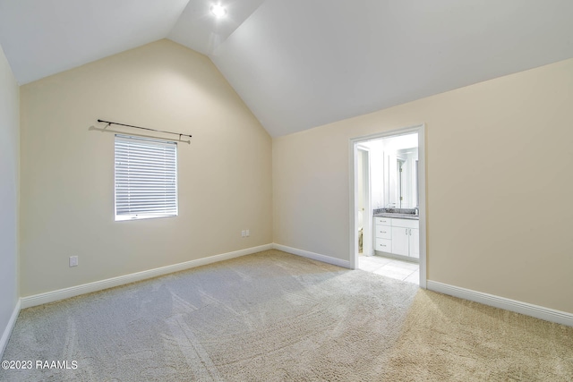 unfurnished room featuring lofted ceiling and light colored carpet