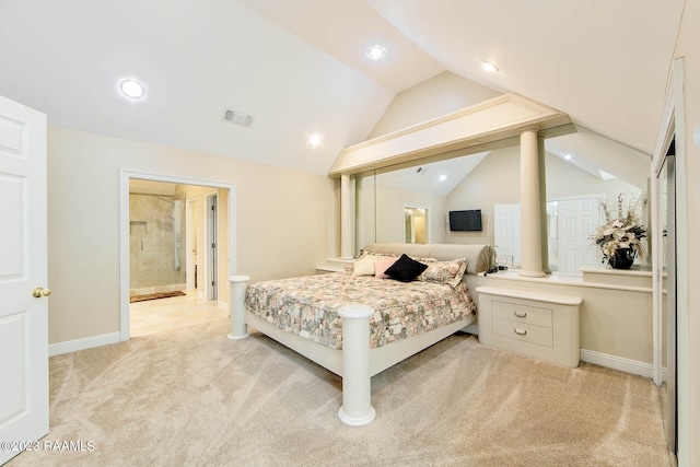 bedroom with ensuite bathroom, light colored carpet, and vaulted ceiling