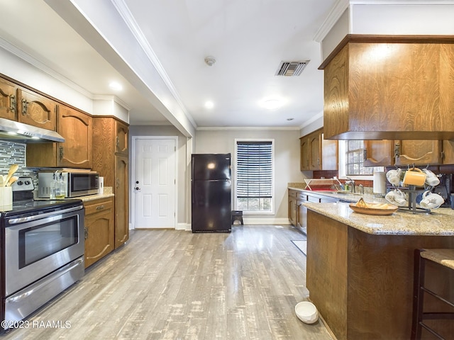 kitchen with crown molding, light hardwood / wood-style flooring, light stone countertops, appliances with stainless steel finishes, and tasteful backsplash