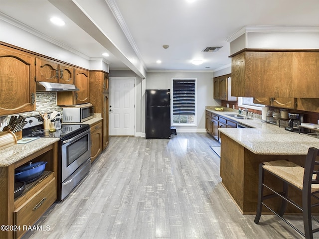 kitchen with ornamental molding, kitchen peninsula, stainless steel appliances, and light hardwood / wood-style flooring