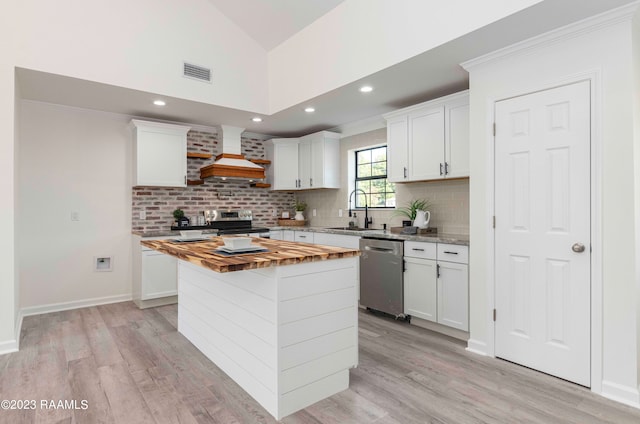 kitchen featuring white cabinetry, backsplash, stainless steel appliances, a center island, and custom range hood