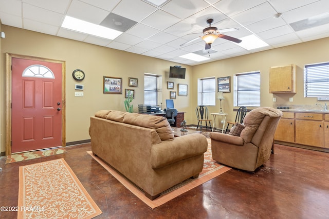 living room featuring plenty of natural light, ceiling fan, and a drop ceiling