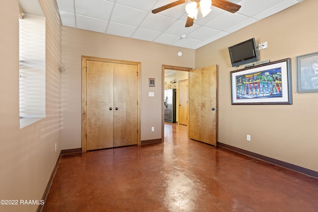 unfurnished bedroom with stainless steel fridge with ice dispenser, a closet, ceiling fan, and a drop ceiling