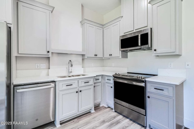 kitchen featuring light hardwood / wood-style flooring, stainless steel appliances, sink, and light stone countertops