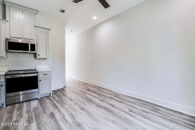 kitchen with light wood-type flooring, stainless steel appliances, and ceiling fan