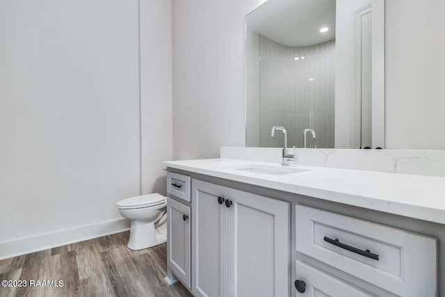 bathroom featuring tiled shower, vanity, toilet, and hardwood / wood-style flooring