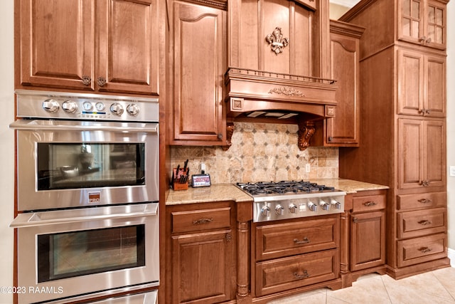 kitchen featuring light tile patterned floors, backsplash, stainless steel appliances, and light stone counters