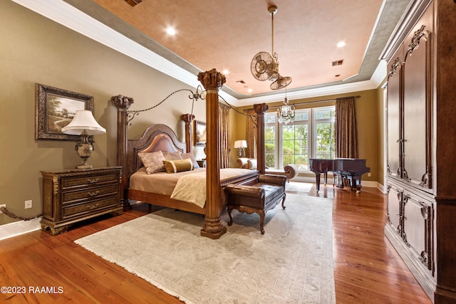 bedroom featuring dark hardwood / wood-style flooring, crown molding, and a tray ceiling