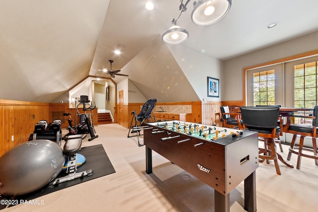 game room with light carpet, ceiling fan, and wooden walls