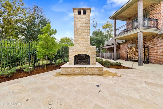 view of patio / terrace featuring an outdoor stone fireplace and a balcony