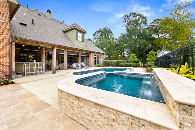 view of pool with a bar, pool water feature, a hot tub, and a patio area