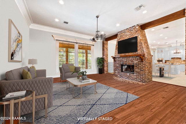 living room featuring a fireplace, wood-type flooring, a chandelier, and crown molding