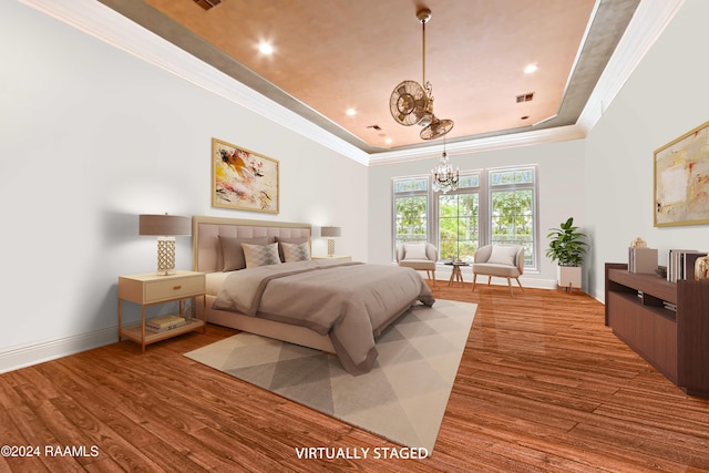 bedroom with a tray ceiling, crown molding, a chandelier, and hardwood / wood-style flooring